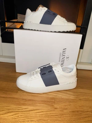 Valentino opens - Säljer nu ett par helt nya Valentino Opens. Dessa är i en grå/mörkblå färg med den klassiska vita basen. Strl 41. Utöver skorna får du oxå med alla tillbehör som syns på sista bilden. Bara att skriva ett DM vid intresse!
