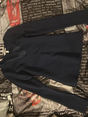 Mörkblå långärmad tröja - En stilren mörkblå långärmad tröja med enkel design och rund hals. Perfekt för dig som gillar minimalistiska plagg. Tröjan har en mjuk känsla och passar till många olika outfits.