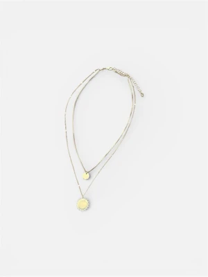 Guldigt dubbelt halsband med medaljonger - Snyggt dubbelt halsband i guldfärgad metall med två tunna kedjor. Ena kedjan har en liten rund medaljong och den andra en större medaljong med dekorativ kant. Perfekt för att ge din outfit en trendig touch. Justerbar längd med kedjeförlängning.