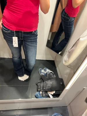 Mörkblå bootcut jeans med kontrastsömmar - Säljer ett par mörkblå bootcut jeans med vita kontrastsömmar och klassisk femficksdesign. Jeansen har en snygg tvätt och är tillverkade i denim med stretch för skön passform. Perfekta för dig som gillar en tidlös och cool look. Passar även storlek S!!!