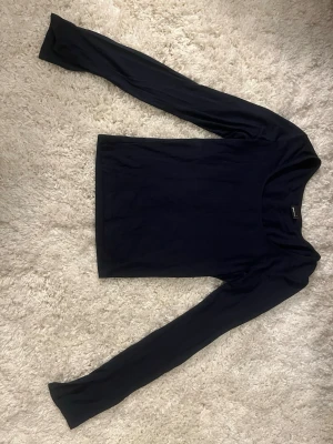 Marinblå långärmad topp Gina Tricot - En enkel och stilren marinblå långärmad topp med slit i ärmarna från Gina Tricot. Modellen har rund halsringning och är gjord i mjuk bomull som sitter skönt mot kroppen. Perfekt att matcha med jeans eller kjol för en clean look.