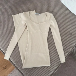 Adoore klänning (storlek 34) - Säljer en Adoore Roma Dress i färgen beige, använd men är i bra skick - fortfarande mycket kvar att ge. Obs: Klänningen har en liten reva baktill vid sprundet, men går att laga (se bild). 