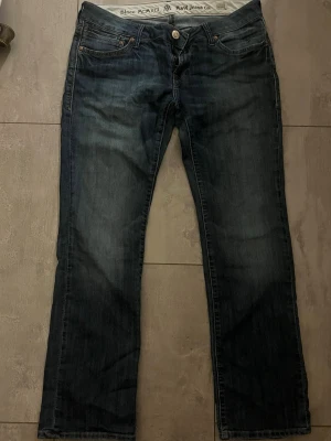 Mörkblå bootcut jeans från Mavi - Snygga mörkblå bootcut jeans från Mavi Jeans Co. Modellen heter Olivia och har klassisk femficksdesign, knappgylf och subtila slitningar för en avslappnad look. Tillverkade i slitstarkt denim med en skön passform. Storlek W31/L30