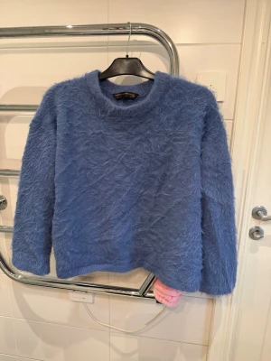 Ljusblå fluffig tröja Pernilla Wahlgren - Supermjuk och fluffig stickad tröja i ljusblått från Pernilla Wahlgren Design. Tröjan har rund halsringning och långa ärmar, perfekt för dig som gillar en cozy vibe. Materialet är lurvigt och ger en riktigt mysig känsla. Samma finns i vitt i min profil!