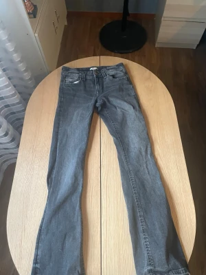 Grå bootcut jeans med broderade fickor - Snygga grå jeans med bootcut-modell och broderade detaljer på bakfickorna. Klassisk femficksdesign och normal midja. Jeansen är tillverkade i denim och har en avslappnad men ändå trendig look.