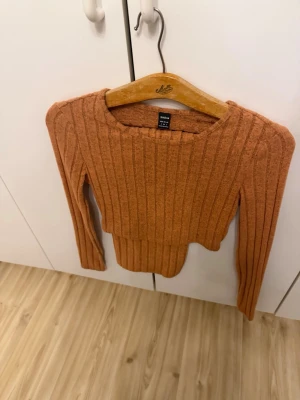 Rostbrun ribbad croptröja SHEIN - Trendig rostbrun croptröja från SHEIN med ribbad struktur och långa ärmar. Tröjan har en rund halsringning och är tillverkad i ett mjukt, stretchigt material som sitter snyggt på kroppen. Perfekt för att lyfta din outfit med en varm färg. Endast testat