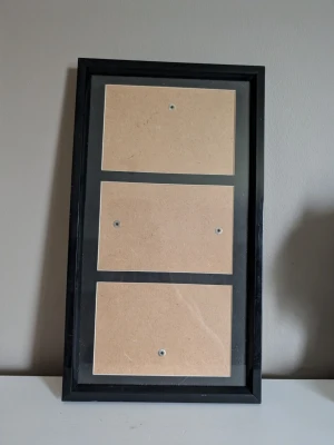 Svart fotoram för flera bilder - Snygg svart fotoram med plats för tre bilder. Ramen är rektangulär och kan användas både stående och liggande. Tillverkad i trä och glas, perfekt för att visa upp dina favoritfoton eller posters på väggen.