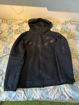 Svart Nike tech - Snygg svart hoodie från Nike med hel dragkedja framtill och huva. Använd fåtal gånger inga täcken på användning. Pris går att diskuteras 