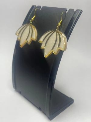 Lotus örhängen i guld och vitt - Unika örhängen i form av blommor med vit och guldig färg. De har en glansig finish och är tillverkade i resin med guldfärgade metalldetaljer. Perfekta för dig som vill ha något annorlunda och snyggt till din stil.