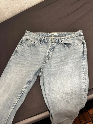 Ljusblå raka jeans från Weekday - Säljer ett par ljusblå jeans från Weekday med klassisk femficksmodell och raka ben. Jeansen har hög midja och är tillverkade i 100% bomull för en autentisk denimkänsla. Perfekta för en avslappnad och trendig look.