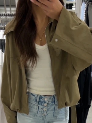 Olivgrön oversized bomberjacka - Snygg olivgrön bomberjacka med dragkedja framtill och bred krage. Jackan har en loose passform och långa ärmar, perfekt för en avslappnad stil. Tillverkad i ett mjukt material som känns bekvämt att bära.