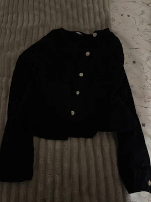 Svart sammetscardigan med silverknappar - Stilren svart jeansjacka i fint jeans material med raka axlar och långa ärmar. Framtill sitter fem stora, runda silverfärgade knappar som ger en cool kontrast. Kortare modell som passar perfekt till jeans eller kjol. Storlek 36 aldrig använd. Från Gina tricot.
