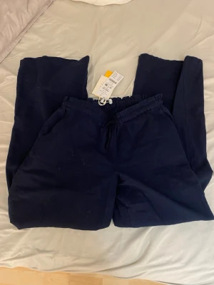 Mörkblå linnebyxor Gina Tricot Young - Snygga mörkblå linnebyxor från Gina Tricot Young med avslappnad passform och dragsko i midjan. Byxorna har sidofickor och är tillverkade i en mjuk linnemix som känns skön mot huden. Perfekta för en chill och stilren look. Köpta för 299 och säljs så mycket billigare!