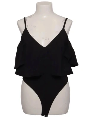Svart off shoulder body - Snygg svart body med off shoulder-design och volang upptill. Djup v-ringning och tunna axelband ger en trendig look. Perfekt att styla med jeans eller kjol. Materialet ser ut att vara mjukt och stretchigt storlek m men passar även S. 