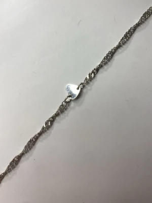 Silverfärgat fot smycke  med hjärta & fjäril - Snyggt fotsmycke  i silverfärg med tunn kedja och två små berlocker, en i form av ett hjärta och en i form av en fjäril. Perfekt accessoar för dig som gillar detaljer och stilrena smycken. Materialet ser ut att vara metall.