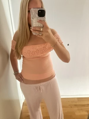 Korall/ljusrosa offshoulder topp med spets - Söt ljusrosa topp med offshoulder-design och dekorativ spetsdetalj med blommönster längs överdelen. Toppen är ifrån Zara barnavdelning men skulle säga att den passar xs!