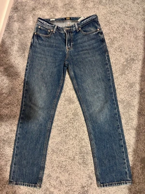 Blå raka jeans från Jack & Jones - Klassiska blå jeans från Jack & Jones med rak passform och fem fickor. Jeansen har normal midja, gylf med dragkedja och knapp samt tydliga sömmar. Tillverkade i denim med en autentisk tvättad look.