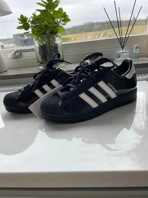 Adidas Superstar svarta och vita sneakers - Säljer ett par klassiska Adidas Superstar sneakers i svart och vitt. Storlek 38,2/3