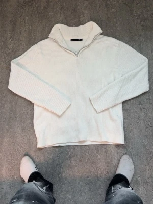 Vit stickad tröja med halvzip - Vit stickad tröja från 157 med halvzip och hög krage. Tröjan har ribbstickad struktur och långa ärmar. Perfekt för lager-på-lager och enkel att matcha med jeans eller joggers.