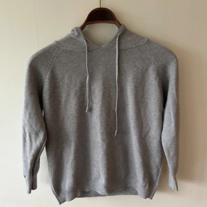 Grå hoodie i kashmir. - En stilren grå kashmir hoodie med huva och snören. Tröjan är i storlek XS och måste säga att den är riktigt skön att ha på sig. Den är helt ny men stod att den var i S på hemsidan och så när den kom var den alldeles för liten.