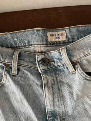 Ljusblå jeans från Tiger of Sweden - Säljer ett par ljusblå jeans från Tiger of Sweden med klassisk femficksmodell och raka ben. Jeansen har en snygg tvätt och är tillverkade i slitstark denim. Perfekta för en avslappnad och trendig look.
