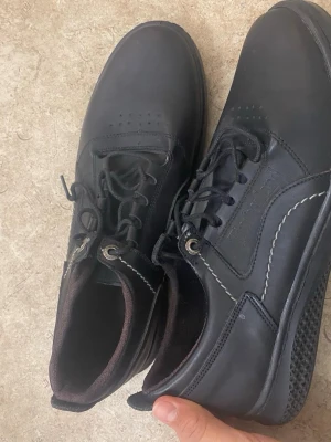 Svarta loafers från Timberland - Säljer ett par svarta loafers från Timberland i läder med vita kontrastsömmar och klassisk snörning. Skorna har en låg profil och diskret logga på sidan. Perfekta för dig som vill ha en stilren och tidlös look.