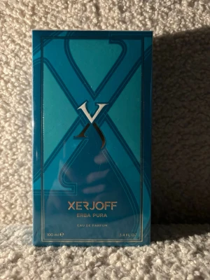 Xerjoff Erba Pura Eau de Parfum oöppnad  - Xerjoff Erba Pura Eau de Parfum i en elegant blå kartong med metallic detaljer. Flaskan rymmer 100 ml och har en lyxig känsla. Doften är känd för sina fruktiga och fräscha noter, perfekt för dig som vill ha något exklusivt och unikt.