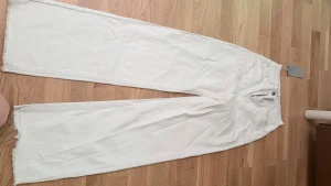 Vita wide leg jeans  - Säljer ett par vita jeans  med wide leg-modell och råa kanter nertill. Jeansen har hög midja, klassiska bakfickor och är tillverkade i bomull. Perfekta för en trendig och avslappnad stil.