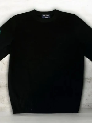 Svart stickad tröja från Fred Perry - Klassisk svart stickad tröja från Fred Perry med rund halsringning och ribbade muddar. Tröjan har en grön broderad lagerkrans på bröstet som signaturdetalj. Perfekt för dig som gillar stilrena och tidlösa plagg i garderoben. Storlek S väldigt liten 170cm Size på kroppen vid best Passning!!!