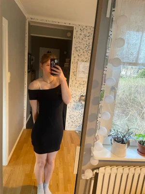 Svart offshoulder kortklänning - Säljer en svart, tight offshoulder kortklänning med slimmad passform. Klänningen har en enkel och stilren design. Materialet känns mjukt och stretchigt, vilket gör den bekväm att bära.