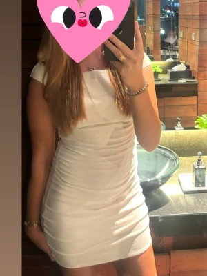 Vit kort klänning med cap sleeve - Snygg vit kort klänning med cap sleeve och figurnära passform. Klänningen har en enkel och stilren design utan mönster, perfekt för dig som gillar en clean look. Materialet ser ut att vara stretchigt och bekvämt, vilket ger en smickrande siluett.