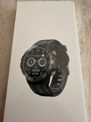 Svart sportig smartklocka - Snygg svart smartklocka med rund urtavla och robust design. Klockan har flera digitala displayer, silikonarmband och metallram. Perfekt för dig som gillar teknik och vill ha koll på både träning och notiser direkt på handleden.