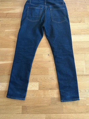 Mörkblå skinny jeans från Salt & Co - Mörkblå skinny jeans från Salt & Co med klassisk femficksdesign och kontrastsömmar. Jeansen har normal midja och smal passform hela vägen ner. Perfekta för en stilren och enkel look.