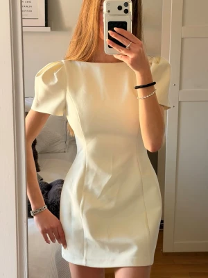 Vit kort figursydd puffärmad klänning från Zara - Stilren vit kort klänning från Zara med markerad midja och puffiga korta ärmar. Den perfekta studentklänningen eller att bara ha i sommar. Helt ny