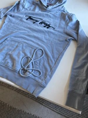 Ljusblå hoodie från Tommy Hilfiger - Ljusblå hoodie med broderad Tommy Hilfiger. Bra till sommarkvällar.