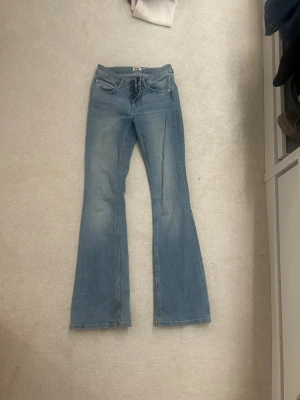 Ljusblå bootcut jeans från 157 - Snygga ljusblå bootcut jeans från 157 med klassisk femficksdesign och dragkedjegylf. Jeansen har utsvängda ben och är tillverkade i mjukt denimtyg som ger en avslappnad och trendig look.