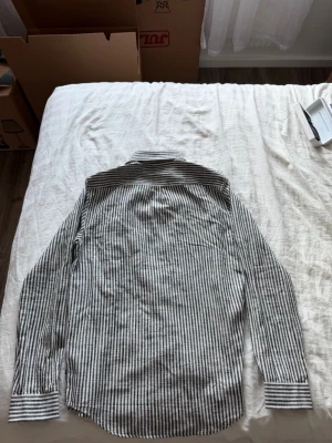 Randig skjorta i linne från Samsoe samsoe - Säljer en snygg vit och svart randig skjorta från Samsoe Samsoe. Skjortan är långärmad, har klassisk krage och knäppning framtill. Tillverkad i linne vilket gör den luftig och perfekt för varmare dagar. Enkel och stilren design som passar till mycket.
