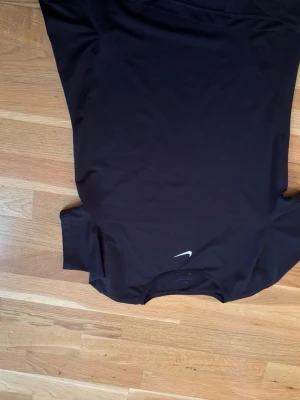 Svart Nike Dri-FIT t-shirt - Snygg svart t-shirt från Nike med Dri-FIT-teknologi som håller dig torr under träningen. Klassisk passform med rund hals och diskret Nike-logga på bröstet. Perfekt för gymmet eller löprundan.