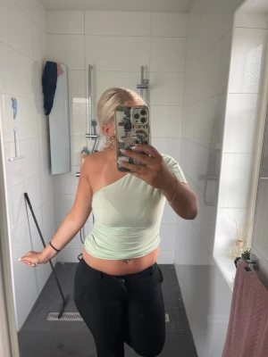 Ljusgrön oneshoulder topp - Snygg ljusgrön topp med oneshoulder-design och tight passform. Perfekt för dig som vill ha en trendig och unik look. Toppen är ärmlös och har en mjuk, stretchig känsla.