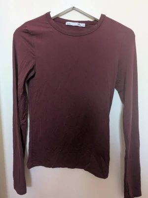 Mörkröd långärmad topp  - En enkel och stilren vinröd långärmad topp. Modellen är figurnära med rund halsringning och tillverkad i ett mjukt och stretchigt material som känns skönt mot huden. Perfekt att matcha med jeans som ett basplagg eller kjol för en clean look. Har använt den ett fåtal gånger, säljer den för att den inte är i min storlek och inte passar. Skriv om ni har några frågor 💕