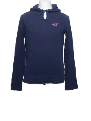Mörkblå hoodie från Hollister - Mörkblå hoodie från Hollister med klassisk huva och dragsko. Liten broderad logga i rött och vitt på bröstet. Tillverkad i mjukt bomullsmaterial och har långa ärmar. Perfekt för en avslappnad och stilren look.