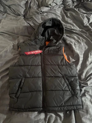 Svart dunväst med huva Alpha Industries - dunväst med huva Alpha Industries. Väldigt bra skicka. Nypris 1600kr