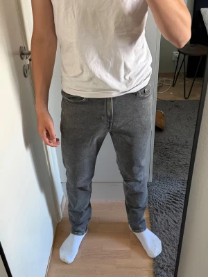 Grå slim fit jeans från HM - Snygga grå slim fit jeans med klassisk femficksdesign och normal midja från HM. Jeansen har en stilren look och passar perfekt till en avslappnad streetstyle. Tillverkade i mjuk denim med lite stretch för extra komfort.