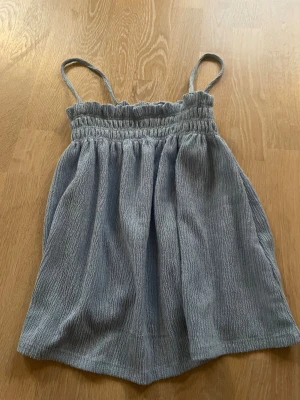 Ljusblå linnetopp från Gina Tricot - Säljer en ljusblå linnetopp från Gina Tricot med smala axelband och smockad överdel. Toppen har en luftig och avslappna. Materialet är mjukt och har en lätt struktur för extra komfort. Passar både XS och S!