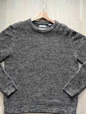 Jack & Jones stickad tröja - Melange XL - Denna stickade tröja från Jack & Jones är i normal passform för en vardaglig look. Tröjan är i mycket gott skick trots användning. Inga tecken på slitage eller smuts.