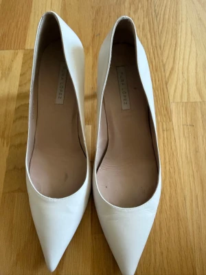 Vita läder pumps  från PURA LOPEZ  - Snygga vita läder pumps från PURA  LOPEZ med spetsig tå och smal klack. Skorna är tillverkade i läder och har en klassisk, elegant siluett som passar till många olika looks.