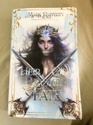 Heir of Broken Fate av Mads Rafferty - Fantastisk skönlitterär bok med magiskt omslag i blått, vitt och guld. Boken handlar om Delilah Covington, arvtagare till tronen, och utspelar sig i en värld där Fae-folket försvunnit. Perfekt för dig som gillar fantasy, äventyr och mystik. Boken är även på engelska☺️