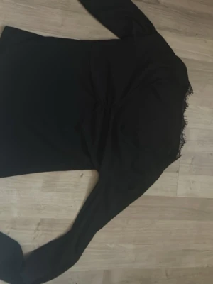 Svart långärmad topp med spets - Svart långärmad topp med v-ringning och fina spetsdetaljer vid halsen. Toppen har rynkade detaljer framtill som ger en snygg form. Perfekt att styla med jeans eller kjol för en trendig look. Är i storlek S men passar ändå M, varumärke är oklart då jag fått den men skulle nog tro h&m 
