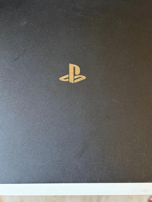 Sony PlayStation 4 Pro svart konsol 1tb med fifa 18 - Säljer en svart PlayStation 4 Pro från Sony. Konsolen har en stilren, matt finish med det klassiska PlayStation-logotypen i guld på ovansidan. Den har en rektangulär form med tre lager och är tillverkad i plast. Perfekt för gaming och streaming. Den har 3 stycken kontroller som funkae bra den vita bara låter när du skakar den