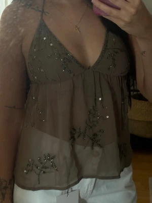 Paljett/glitter topp  - Fin khaki färgad halterneck top med öppen rygg, använd en enstaka gång förra sommaren så den är i väldigt fint skick, har klippt bort lappen då toppen är genomskinlig men det är storlek XS 